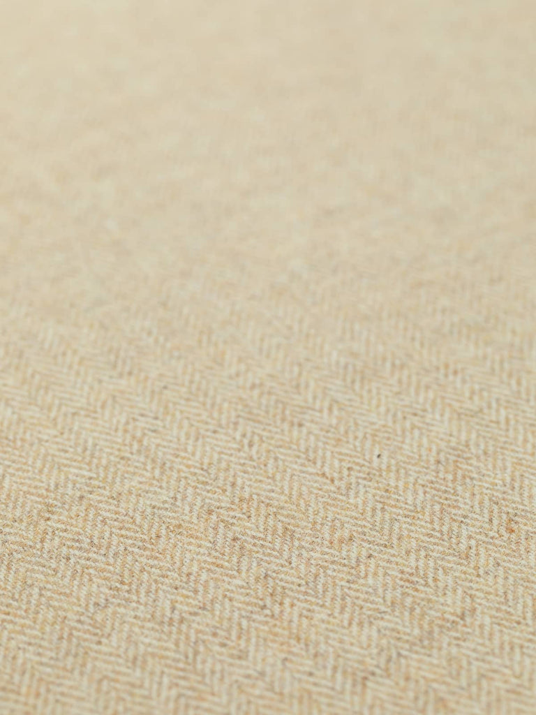 Angled detailed close-up of Yorkshire Tweed Herringbone in Grandma's Shortbread, showing the flat weave and finely woven chevron pattern. The natural cream and buttery golden tones create a rich, comforting fabric ideal for classic, timeless fashion and upholstery.