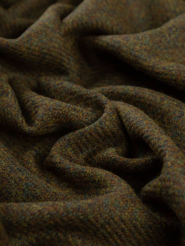 Angled twist shot of Verdant Vale Tweed showing its earthy brown, green, and teal twill weave with subtle depth and a softly structured wool texture.