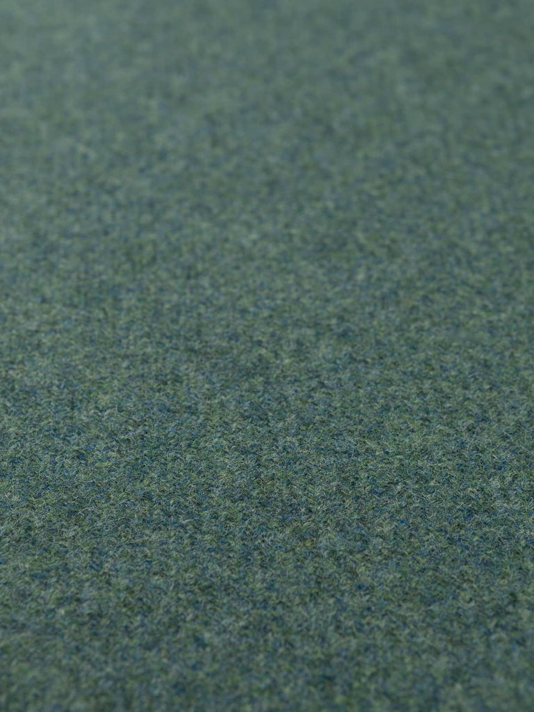 Flat angled shot of the Heathfield tweed highlighting its muted green, teal, and grey tones and the subtle depth of its classic Yorkshire twill weave.
