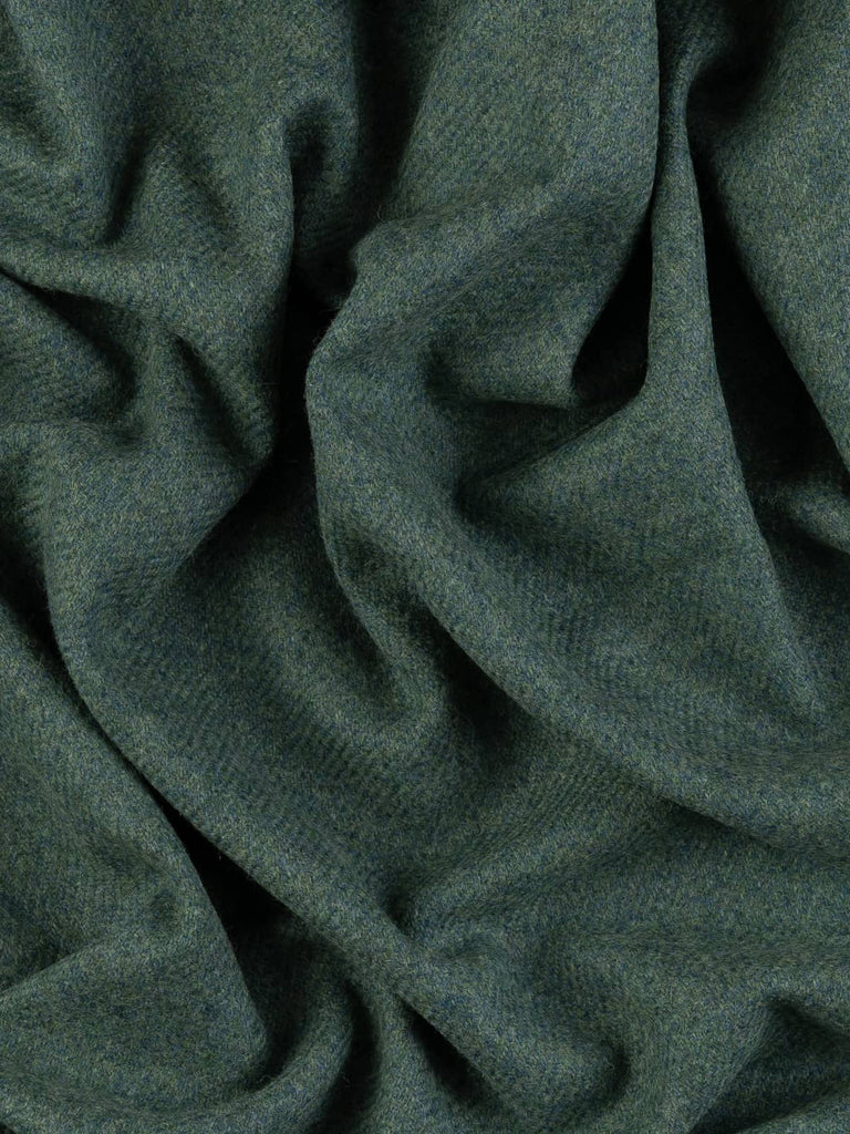 Aerial twist shot of Heathfield Yorkshire Tweed revealing its rolling-dales colour palette of green, teal, and grey and its softly textured twill surface.