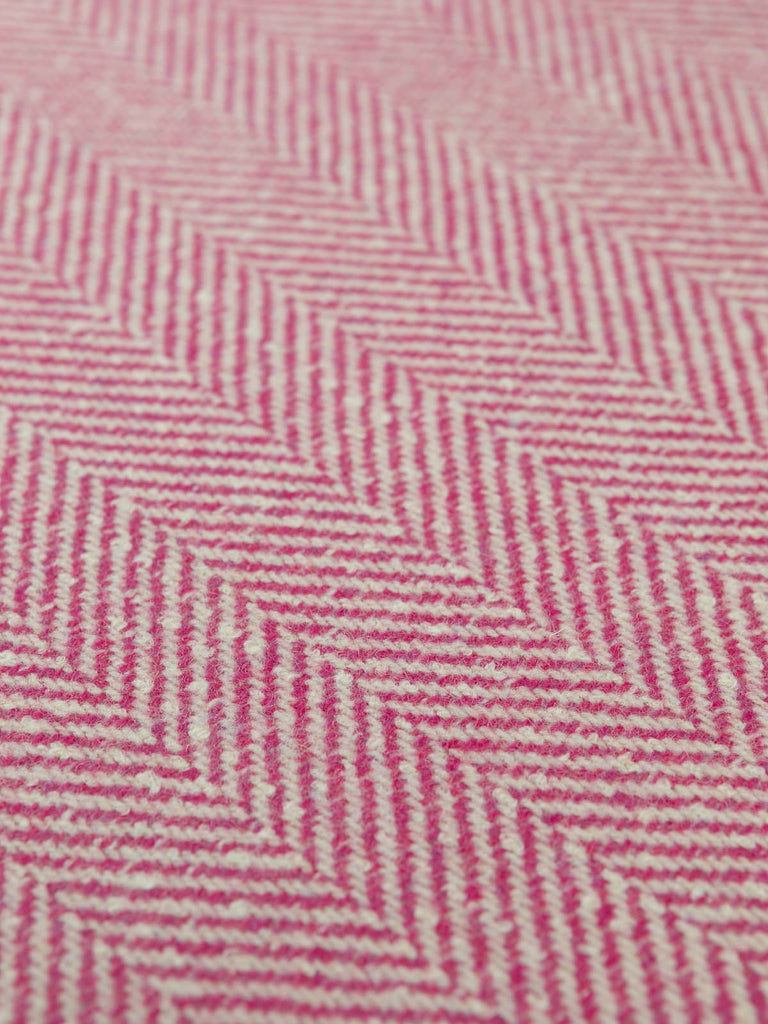 Flat angled shot of the jumbo herringbone tweed highlighting the contrasting winter-white warp and vibrant fuchsia weft in its oversized lambswool chevron pattern.