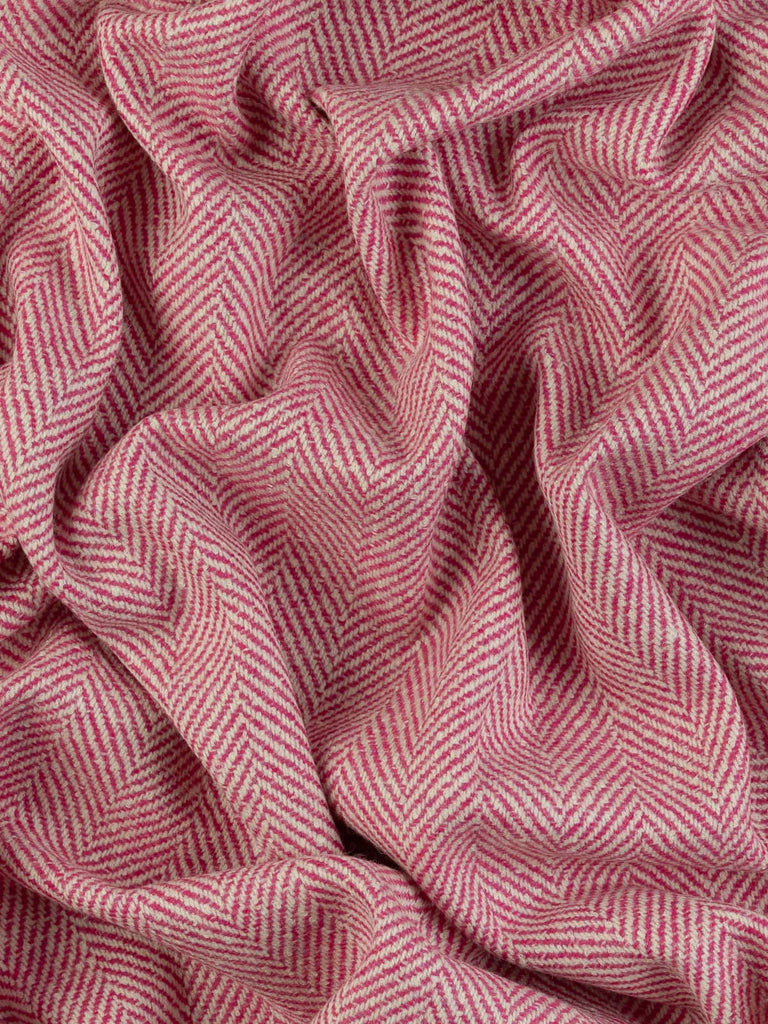 Aerial twist shot of the lambswool jumbo herringbone revealing the plush, lightly felted texture and striking winter-white and fuchsia colour contrast.