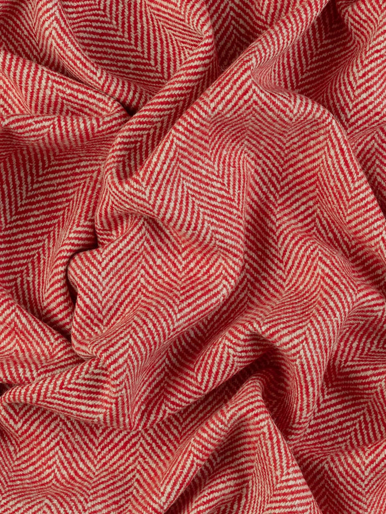 Aerial twist shot of the jumbo herringbone lambswool tweed revealing its plush, lightly felted texture and festive holly-red and natural-white chevron design