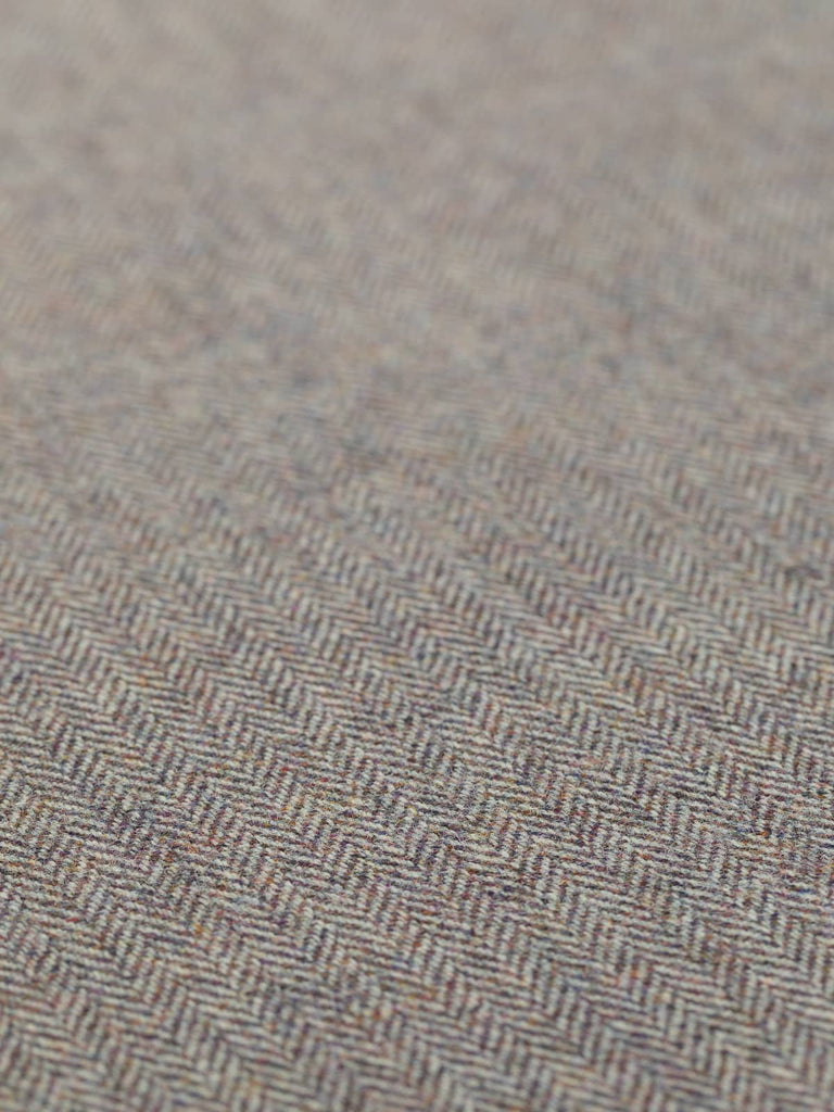 A detailed flat image of Heather Momento, emphasizing its warm, autumnal tones and refined herringbone pattern. The blend of purple, rust, and gold hues against the soft grey warp yarns evokes the beauty of heather-covered moorlands. The medium-weight wool fabric displays a luxurious tweedy texture, ideal for crafting timeless and stylish garments.