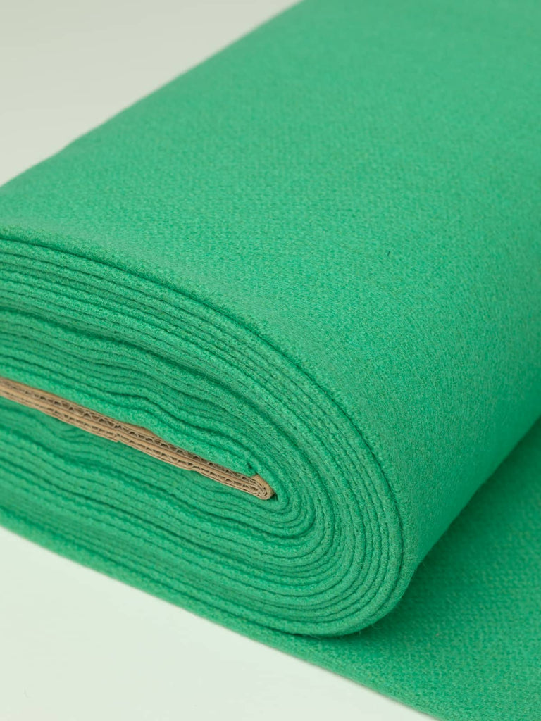 Angled roll of Mint Macaron Twill Melton wool, 600gsm, showing soft peppermint green shade with light-reflecting sheen and dense felted finish