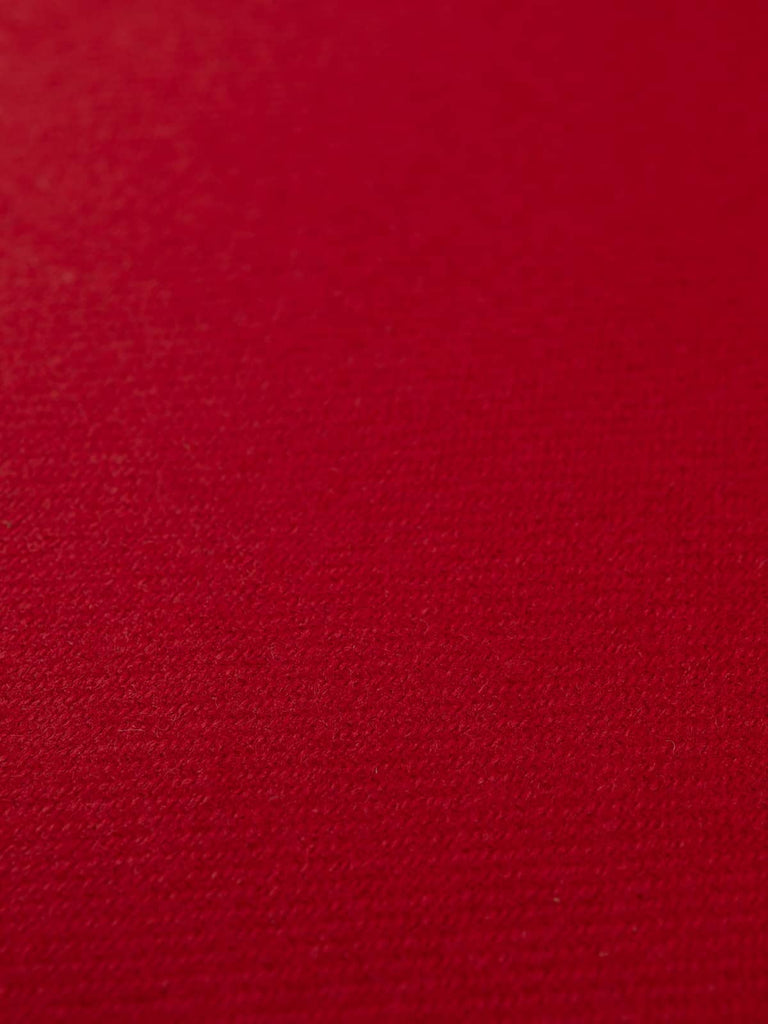 Flat angled shot of Winter Hearth tweed highlighting its deep red melange, smooth twill weave, and warm, weighty wool texture.