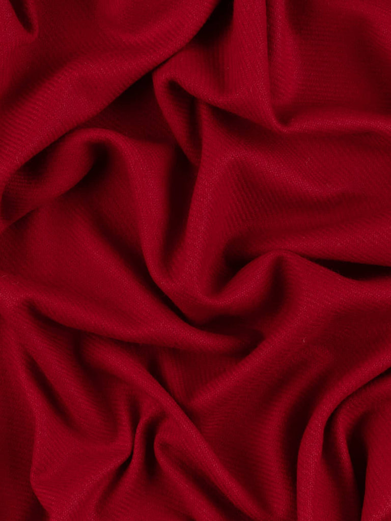 Aerial twist shot of Winter Hearth wool tweed revealing its structured twill, vibrant holly-berry red tones, and tactile medium-heavy wool handle.