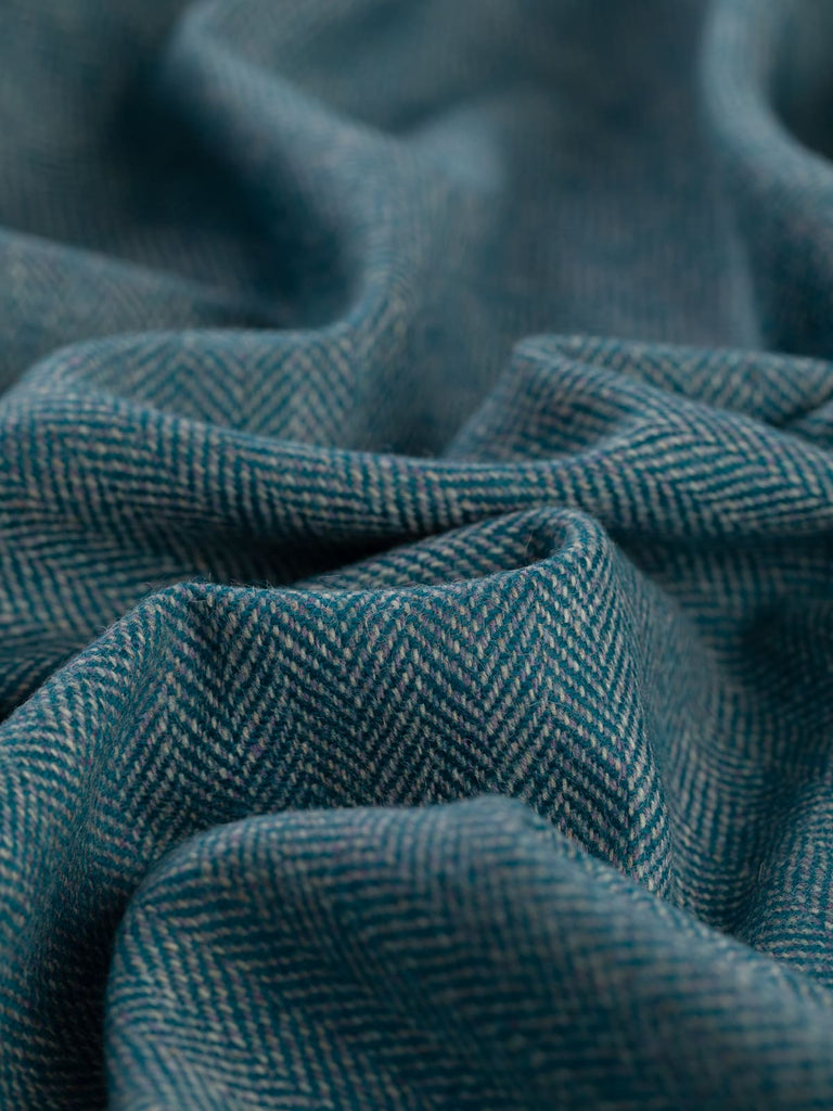 Detailed shot of the Eco Herringbone Yorkshire Tweed in Teal Tale, focusing on the refined herringbone weave. The combination of soft heathered lilac, natural beige, and marled grey yarns creates a misty effect, enhanced by the deep teal accents.