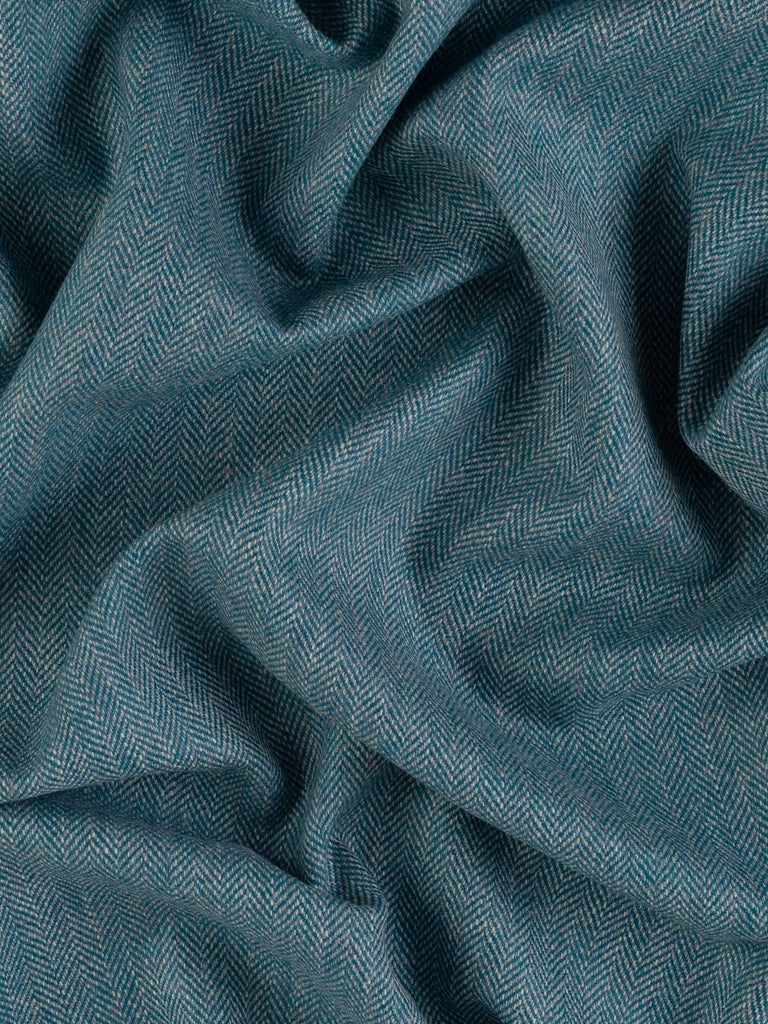 Aerial view of Eco Herringbone Yorkshire Tweed in Teal Tale, twisted to reveal the full width and pattern. The fabric’s rich teal and lilac hues, along with its distinctive herringbone design, are prominently featured.