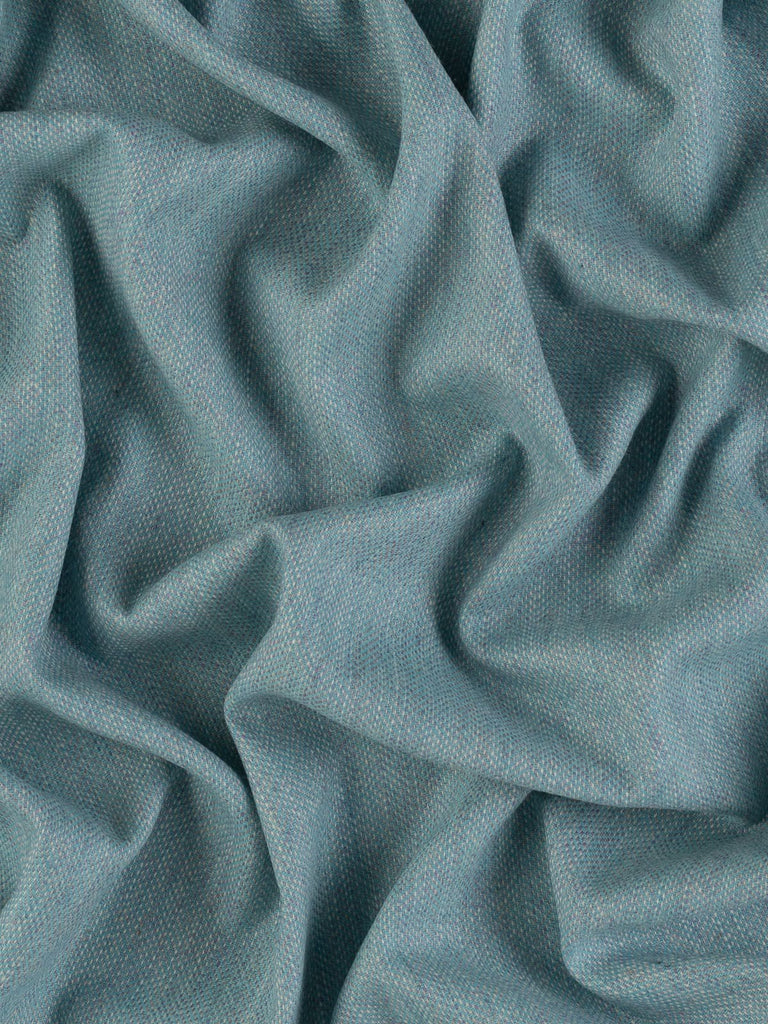 Aerial view of Eco Herringbone Yorkshire Tweed in Frosted Valley, twisted to display the full width and pattern. The fabric’s cool aqua and lilac hues, combined with its distinctive herringbone weave, are beautifully showcased.