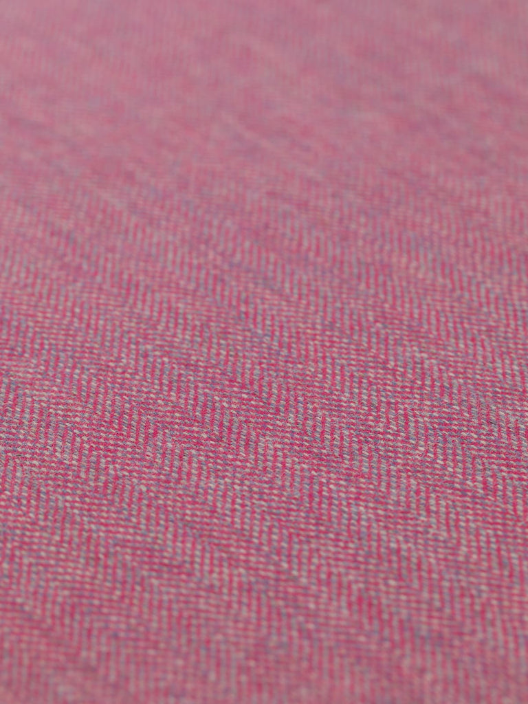 Angled detailed close-up of Eco Herringbone Yorkshire Tweed in Campion Crush, focusing on the flat weave and vibrant pink with lilac undertones. The distinct herringbone pattern and the fabric’s subtle texture are clearly visible.