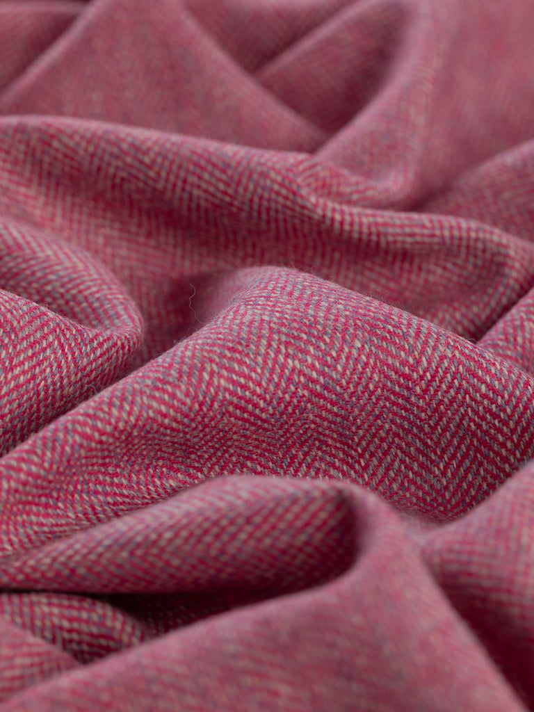 Angled close-up of twisted Eco Herringbone Yorkshire Tweed in Campion Crush, showcasing the lively pink and lilac hues. The herringbone pattern and soft texture are prominent, emphasizing the fabric's intricate weave.