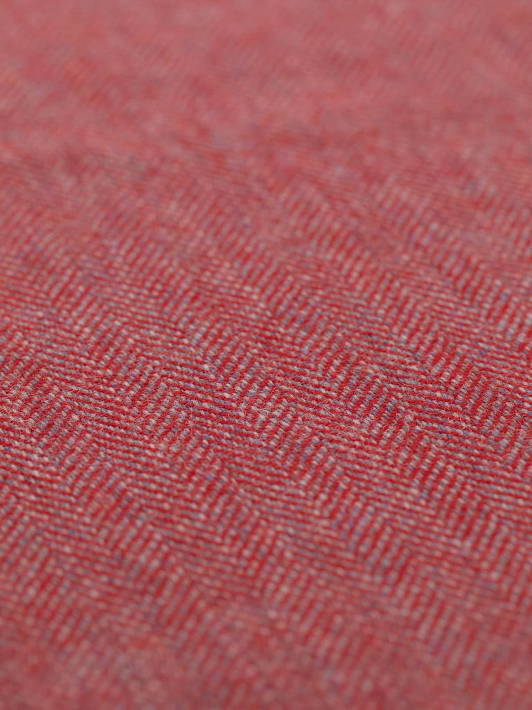 Angled detailed close-up of Eco Herringbone Yorkshire Tweed in Rocking Robin, focusing on the flat weave and contrasting red and lilac hues. The herringbone pattern is prominent, resembling the feathered look of the robin.