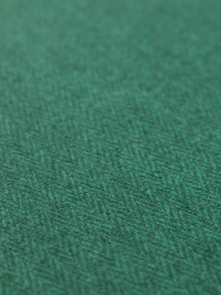 Angled flat view of Forest Tides herringbone wool tweed, 154cm wide, featuring deep teal and evergreen melange yarns that create a textured, organic chevron pattern with subtle sheen and heritage structure
