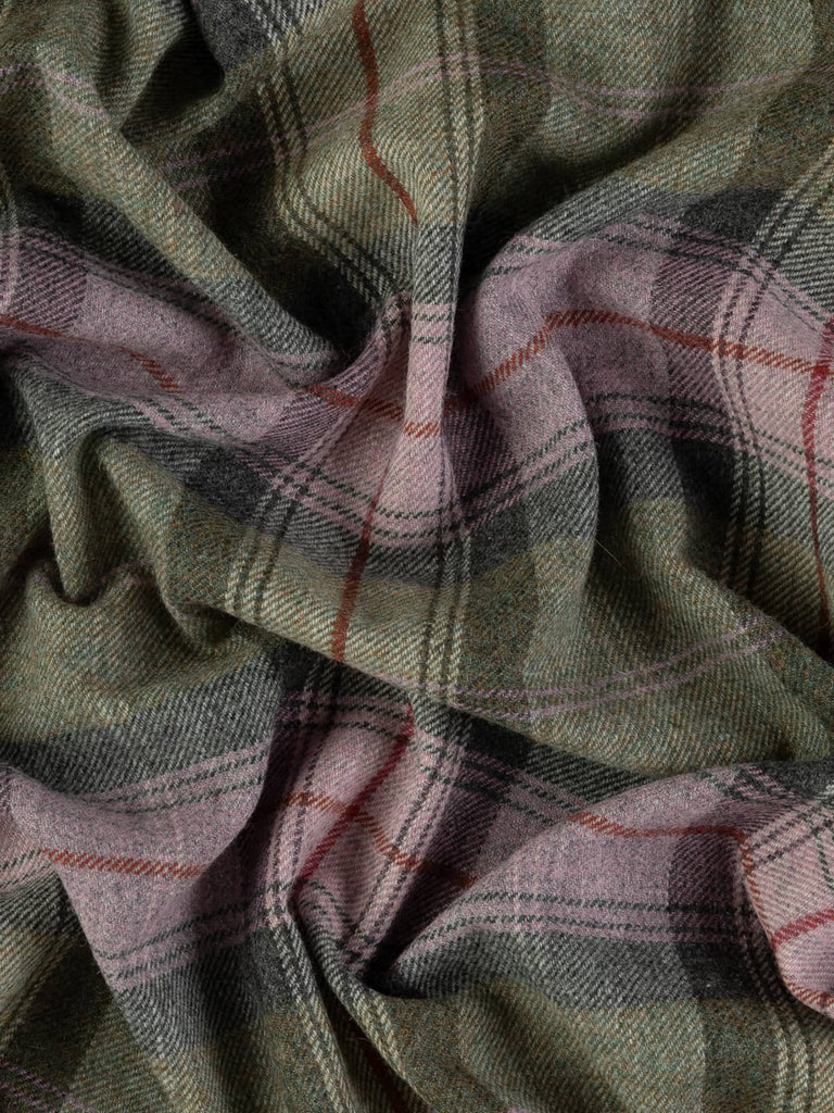 Overhead flat shot of Heathshore Mist Yorkshire woollen plaid, capturing natural heathland palette of lilac thrift, earthy green, and grounding greys intersected by bold red accent stripe