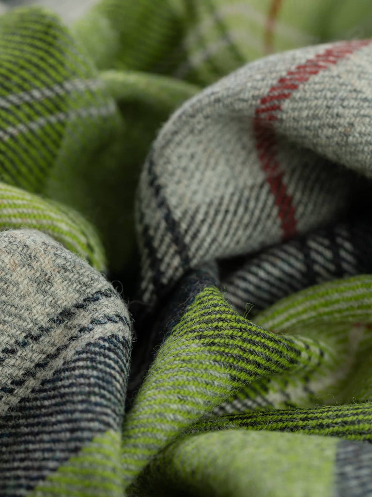 Twist of Green Awakening Yorkshire Tweed plaid, 100% wool, 155cm wide, showing yellow-green new shoot tones, soft misty greys, charcoal checks, and signature Bloodline red overcheck