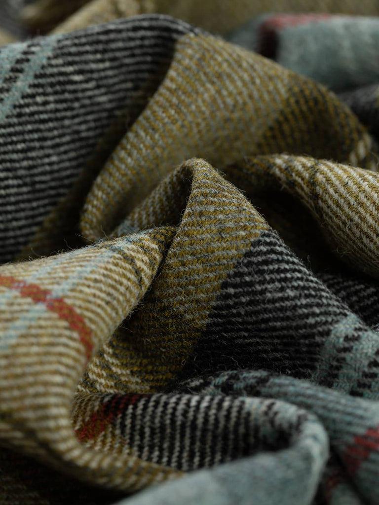 Twist of Kelpline Tweed Yorkshire plaid, 100% wool, 155cm wide, showing olive-gold green with seaweed hue, mineral blue melange, heathered grey, and bold Bloodline red overcheck