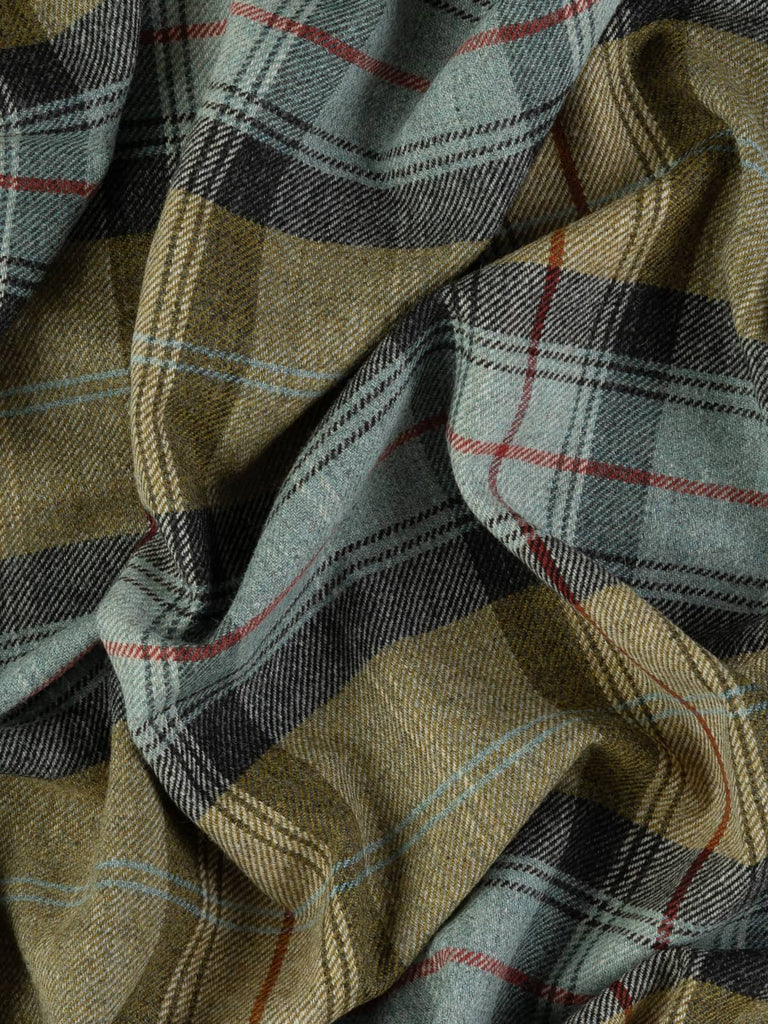 Overhead flat shot of Kelpline Tweed Yorkshire woollen plaid, capturing seaside tones of olive green, mineral blue, weathered grey, and vivid red accent stripe across rugged wool texture