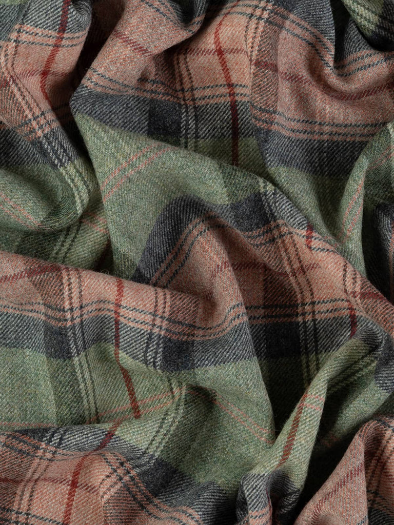 Overhead flat shot of Heathland Blush Yorkshire woollen plaid, capturing muted autumn hues of grey-blue green, stormy navy, faded coral blush, and signature red overcheck across rugged wool texture