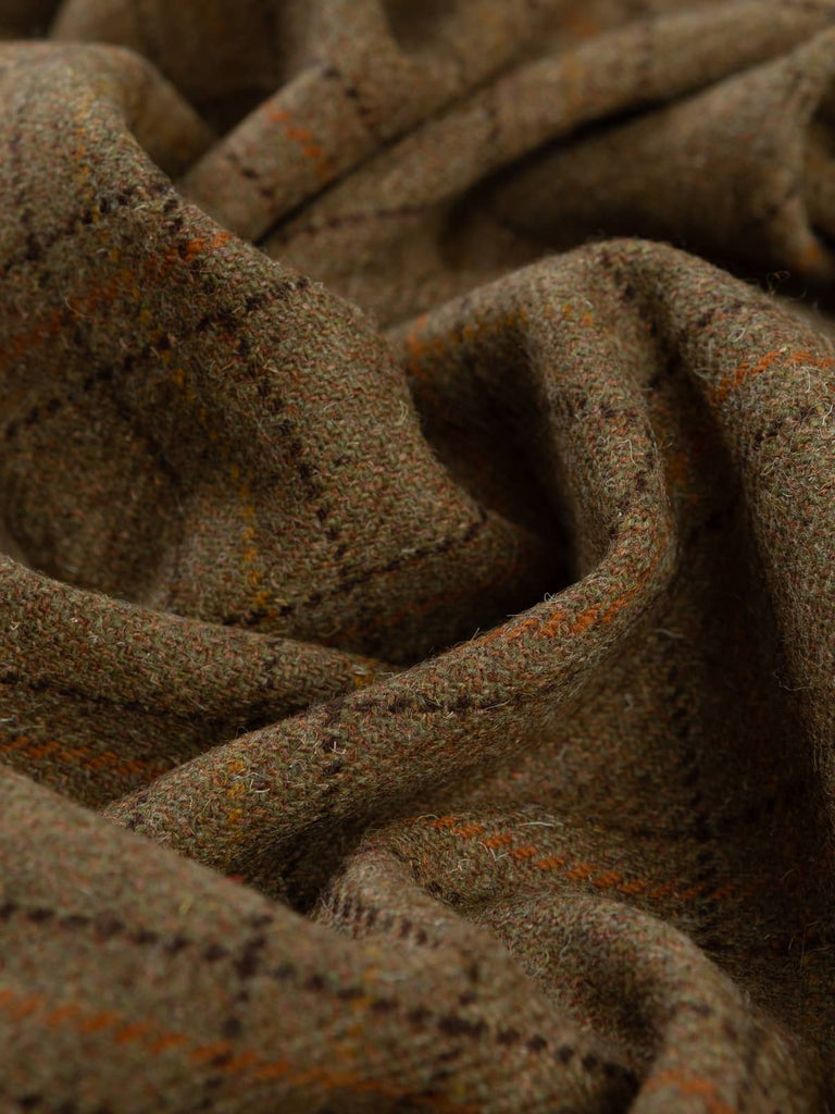 Angled twist shot of Moorland Ember tweed showing its rustic windowpane checks, mottled bracken-brown and moss-green base, and warm peat, gold, and rust overchecks.