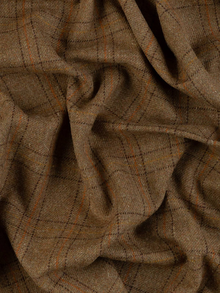 Aerial twist shot of the Moorland Ember wool tweed highlighting its textured melange base and layered windowpane checks in peat, gold, and rust tones.