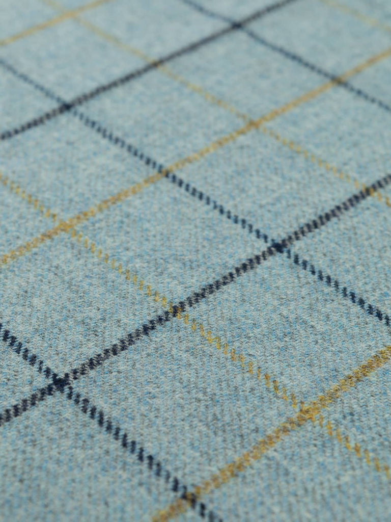 Angles flat shot of Harborton tweed, highlighting the cool grey base, subtle maritime blues, and crisp navy and golden-green windowpane lines in a clean flat layout.