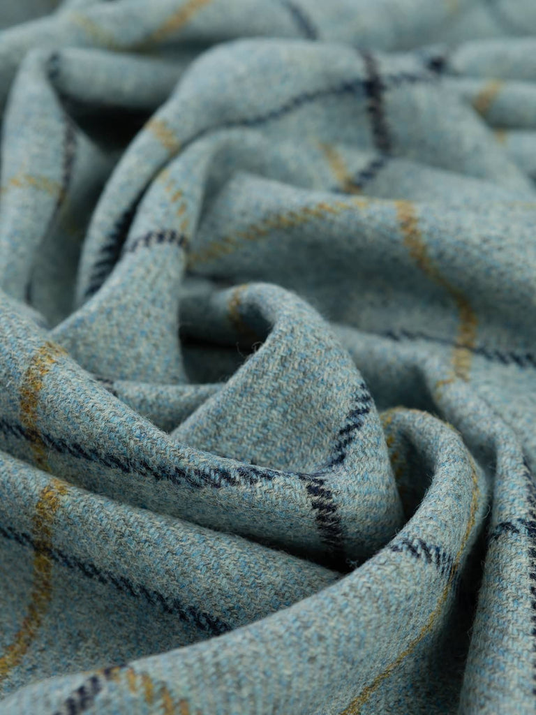 Aerial twist shot of Harborton fabric, capturing twisted folds from above and emphasising the sea-and-sky palette, maritime greys, blue glints, and structured heritage overchecks.