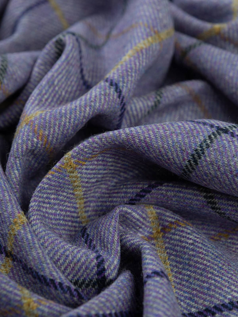 Angled twist shot of Winter Pansies Yorkshire Tweed, showing the purple and grey melange base with navy and sunshine-gold windowpane checks twisting through the folds.
