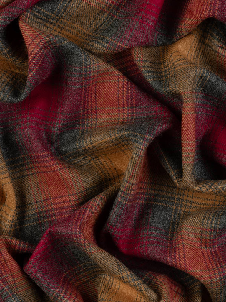 Aerial twist shot of Fireside Glen Check tweed, capturing twisted folds from above to reveal subtle grey-green depth and luminous amber and ember-red overchecks.