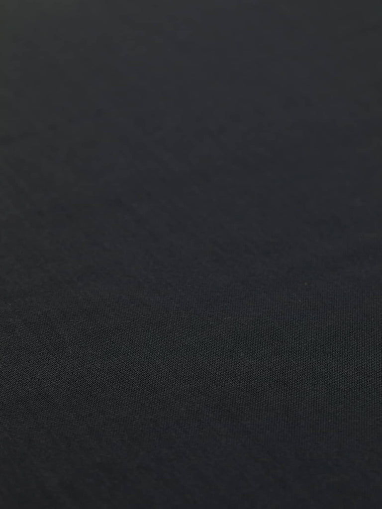 Spread-out view of the Charcoal Wool Blend Utility Serge fabric, displaying its almost-black hue and finely grainy texture. The close, superfine twill weave is visible, highlighting the fabric’s durability and crease-resistant qualities.

Alt Text 3 (Close-Up of Weave and Texture): Close-up of the Charcoal Wool Blend Utility Serge, showcasing its dense, superfine twill weave and slightly grainy texture. The fabric’s robust construction makes it perfect for utility jackets, aprons, and other stylish, hardwea