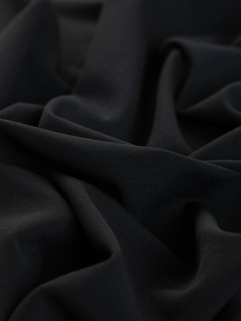 Close-up of the Charcoal Wool Blend Utility Serge, showcasing its dense, superfine twill weave and slightly grainy texture. The fabric’s robust construction makes it perfect for utility jackets, aprons, and other stylish, hardwearing garments.