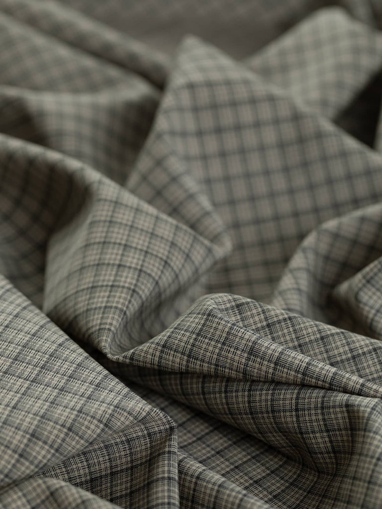 Close-up shot of Iced Latte Chequerboard fabric, emphasizing the intricate chequerboard weave pattern in soft taupe and grey tones. The light wool blend with elastane provides gentle stretch, excellent stability, and a refined drape quality, making it perfect for suiting, corporate wear, and trendy utility styles.