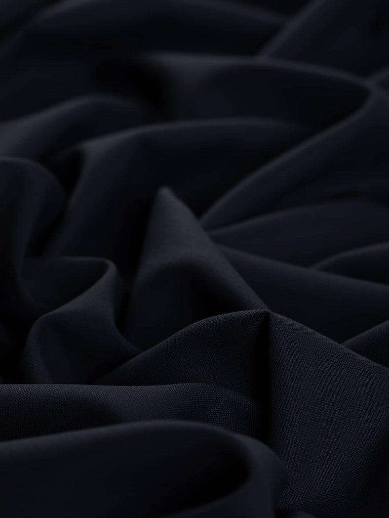 Close-up of Navy Zenith’s finely woven texture, showcasing the subtle honeycomb-like weave and dark navy color. The fabric's tightly twisted yarns create a slightly textured, non-irritant surface with a beautiful fluid drape. It is ideal for crafting smart suits, wide-leg trousers, waistcoats, and classic shirt dresses with a timeless appeal.