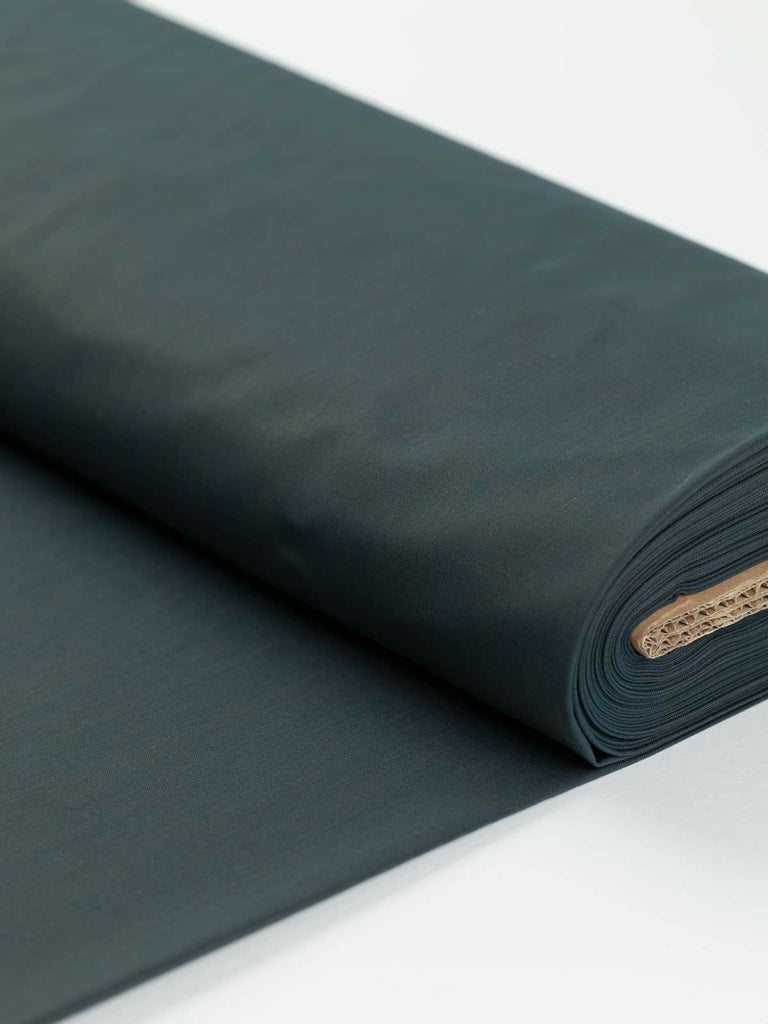 100% Virgin Wool Ocean Mystery fabric folded, displaying its rich khaki olive and Prussian blue shot effect, evoking the deep, changing colors of the ocean. This fine Italian worsted is lightweight yet durable, perfect for sophisticated tailoring.