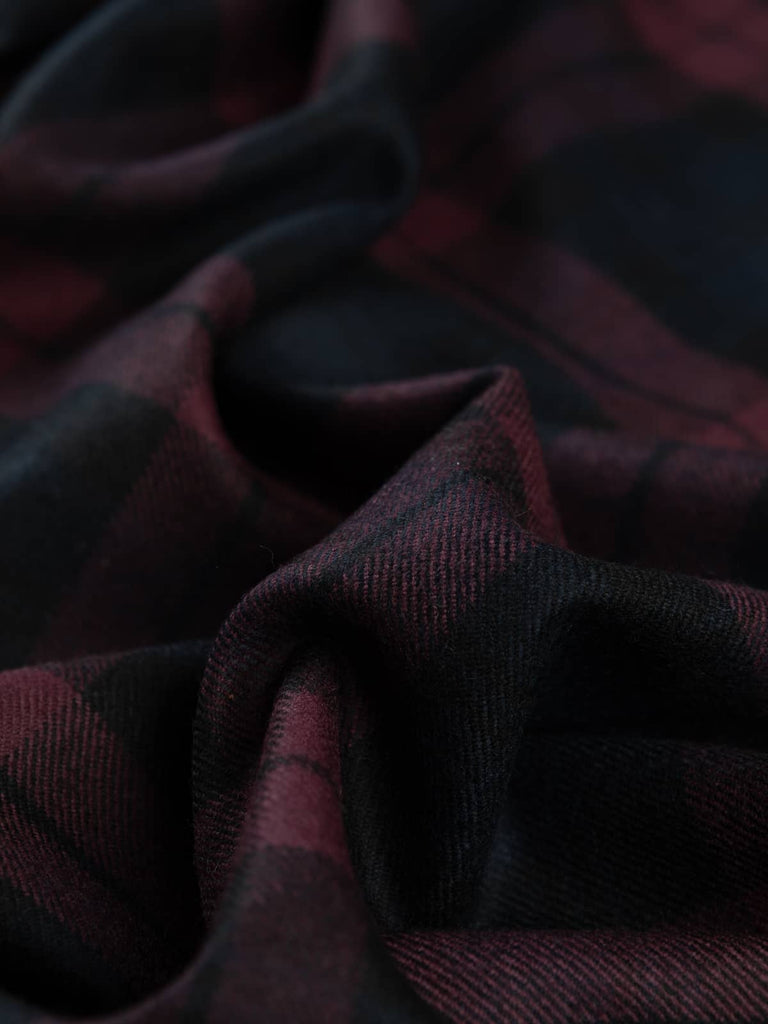 Twist of Plum Watch Tartan highlighting its luxurious lambswool texture and darkly decadent tones of plum, navy, and black with subtle twill sheen.