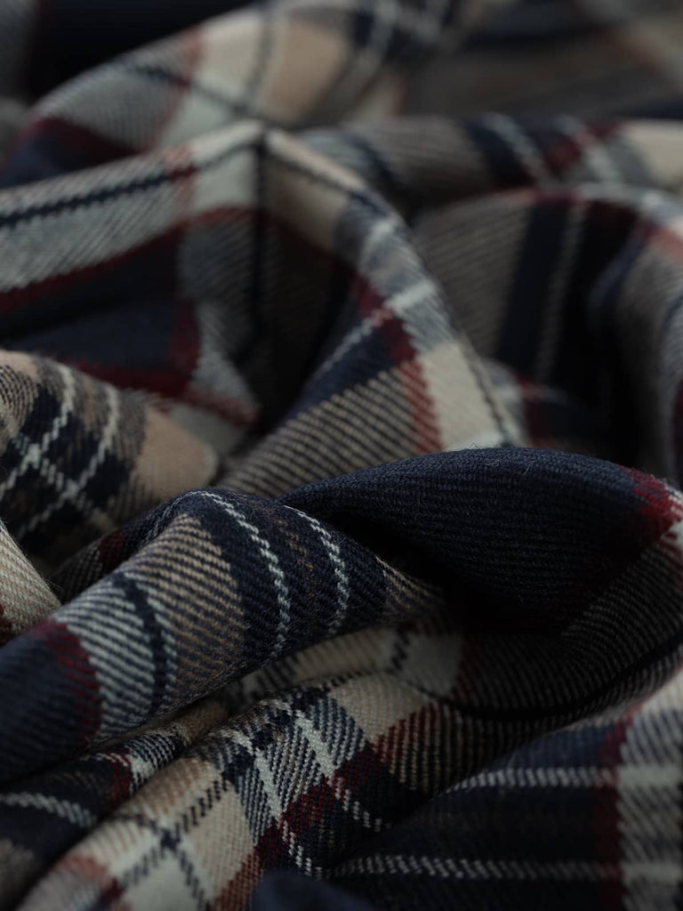 Twist of Stewart Navy tartan 100% wool worsted, highlighting twill weave texture, soft handle, and striking contrast between navy base and red, beige, and white accents