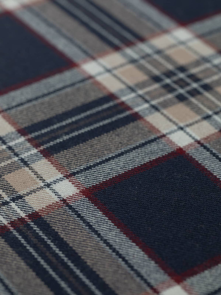 Flat angled view of Stewart Navy tartan fabric, 13cm x 16.5cm repeat, displaying rich navy backdrop with bold grid of red, beige, and white for a refined yet versatile universal tartan