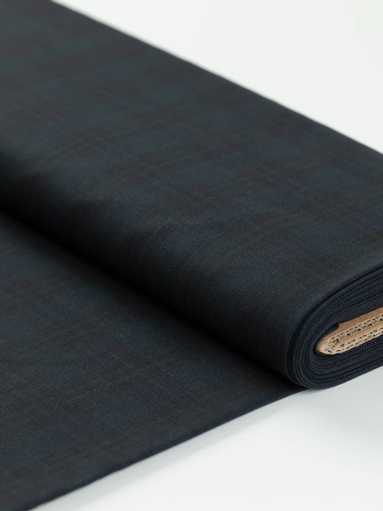 Lazio District Check suiting fabric unrolled, displaying its classic Italian district check pattern in dark denim melange, navy, and pine green tones, ideal for stylish tailored garments.