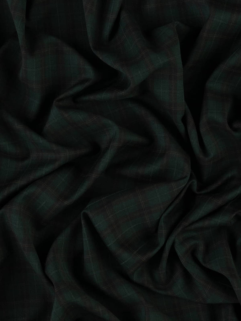 Bosco di Notte Check fabric in 100% Virgin Wool, folded to showcase the subtle windowpane check pattern. The dark spruce green, black, and hazel brown hues create an air of mystery and timeless elegance. The fabric has a light to medium weight with a smooth, soft feel and fine twill weave.