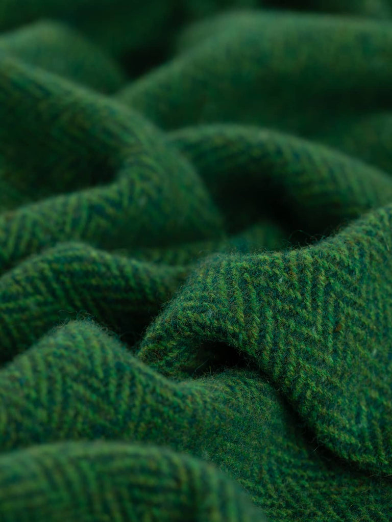 Close-up view of rich, deep resinous pine green tweed fabric, featuring multi-hued fresh grass-green melange yarns and subtle flecks of turquoise, beige, and rust, evoking the natural charm of a verdant forest.