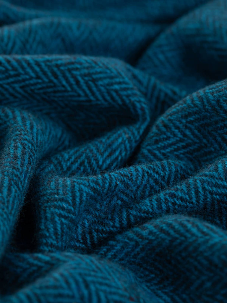 The close-up shot highlights the intricate textures of the Fathomless Blue fabric, showcasing the deep turquoise blue-green and dark navy yarns twisted together, creating a beautiful interplay of colors and a luxurious, tactile quality.