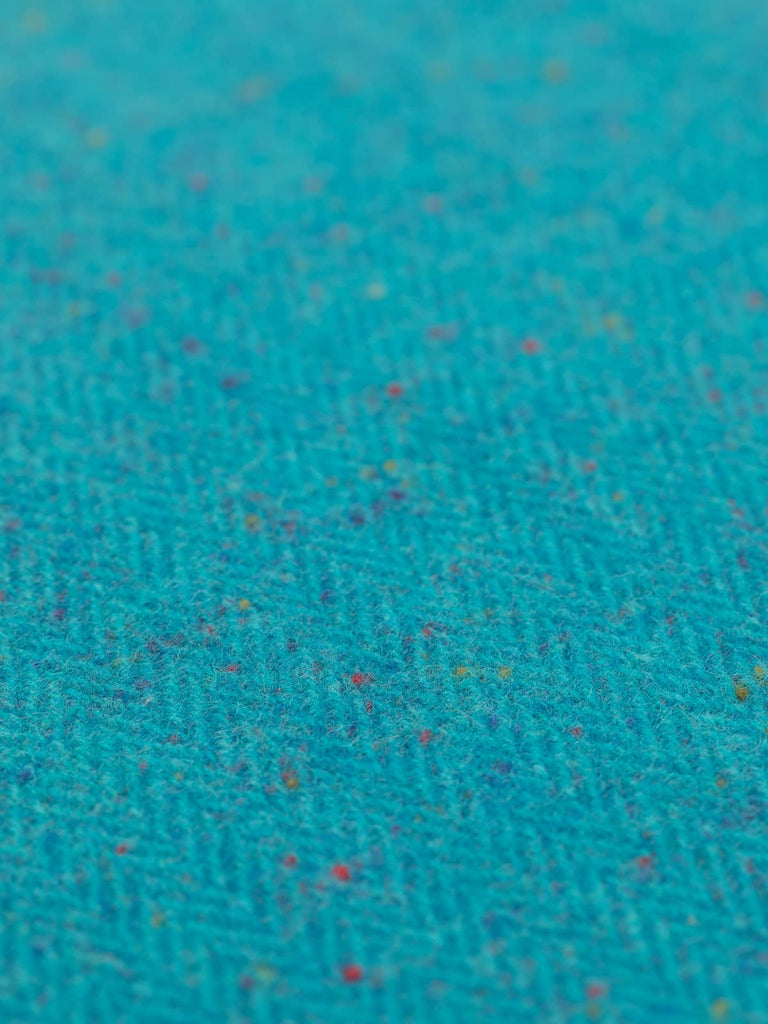 An aerial perspective captures the Electric Turquoise fabric's electrifying colors, where the bright turquoise and flecks of varying hues intertwine to create a fabric that radiates joy and vibrancy, perfect for bold design choices.