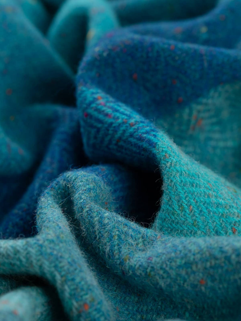 This close-up angle of Treasured Oceans fabric reveals a vibrant array of turquoise and peacock hues, interspersed with glacial tones and joyful Donegal flecks that evoke the shimmering beauty of tropical waters.