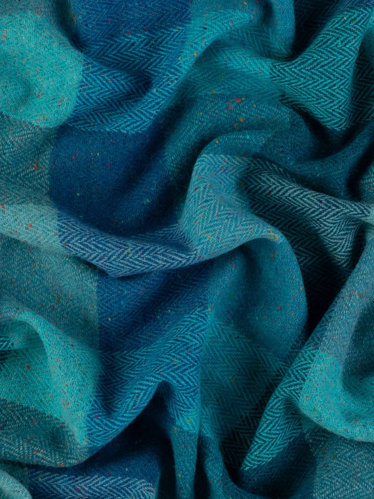 In this aerial shot, the Treasured Oceans fabric displays a captivating blend of oceanic colors and intricate herringbone patterns, with multicolored Donegal flecks that mimic the dazzling effects of bioluminescent sea life.