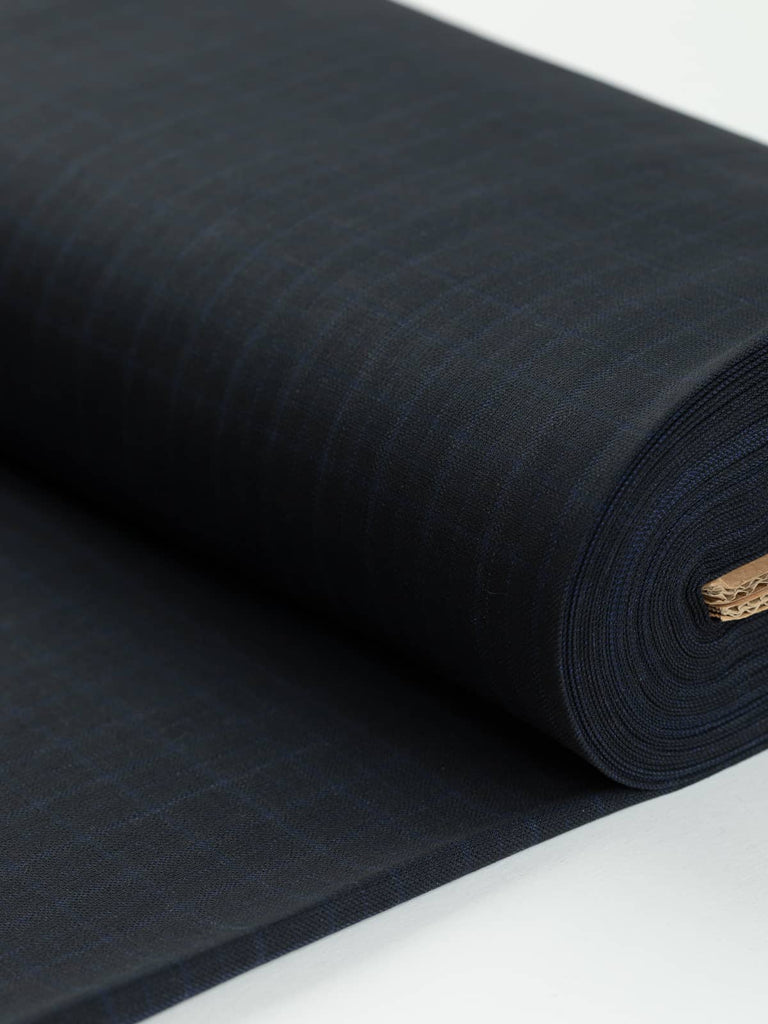 Wool & Viscose Augustus Check fabric folded, showcasing its refined windowpane check pattern in dark navy and Savoy blue tones. This Italian suiting fabric is light/medium weight with a breathable texture, perfect for sophisticated and tailored garments.