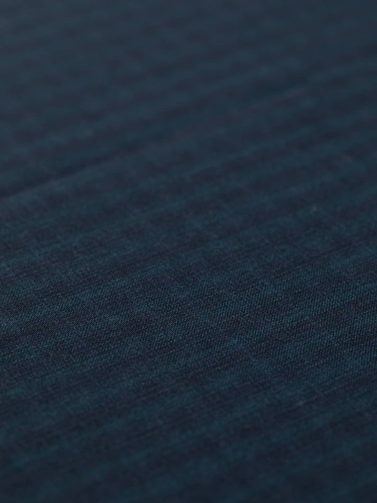 Close-up of the Cosmopolitan Check fabric, highlighting the subtle, flat matte weave and its stylish dark blue check pattern. The 100% Virgin Wool fabric is soft, hard-wearing, and exudes a cosmopolitan appeal for sophisticated clothing.