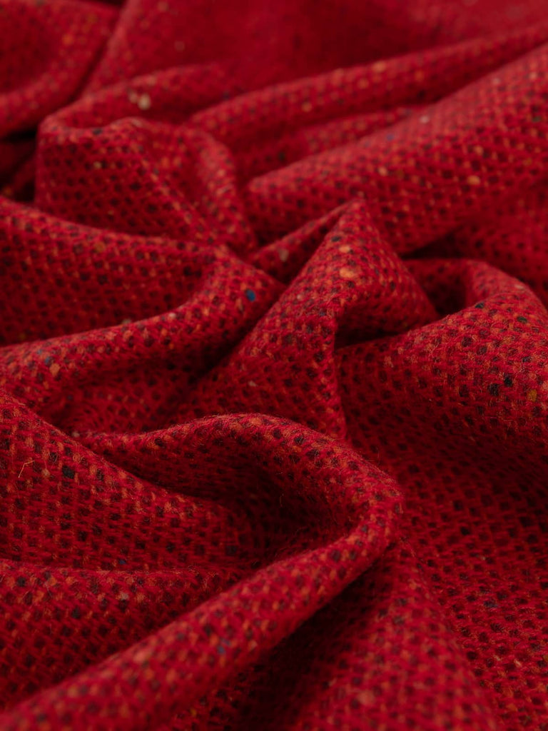 Twist of Ember Glow Donegal Tweed showing rich Pillar Box red, fire orange, and deep wine tones with signature flecked texture and soft brushed wool finish.