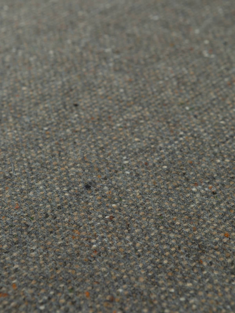 Overhead flat view of Pebble Beach Donegal Tweed, 162cm wide, highlighting muted earthy hues, classic herringbone pattern, and traditional flecked surface.