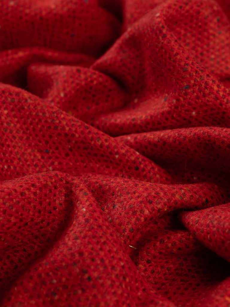 Twist of Capsicum Red Donegal Tweed showing brushed lambswool softness and a hot spice-inspired blend of chilli red, orange, and wine hues with neps.