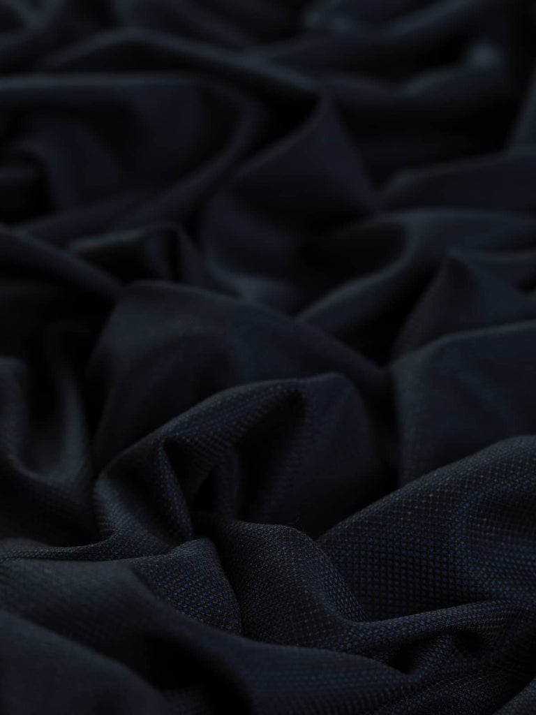 A close-up of a sophisticated suiting fabric showcasing a dark blend of French Navy and Black in a micro diamond weave pattern. The subtle shot effect and lightly brushed surface are visible, adding a touch of luxury.